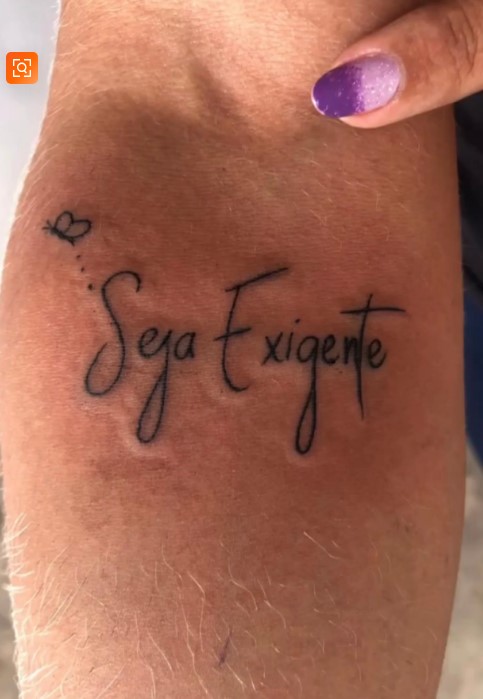 'Seja Exigente' com a borboleta da marca tatuada no braço