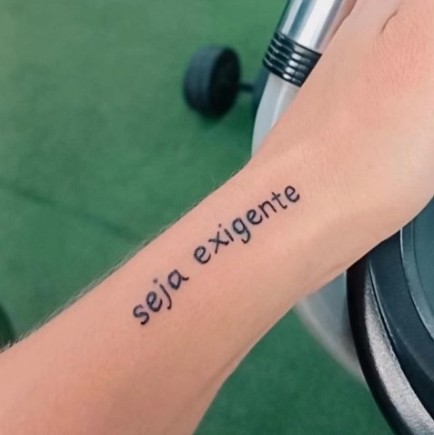 'Seja Exigente' em caligrafia fina no antebraço