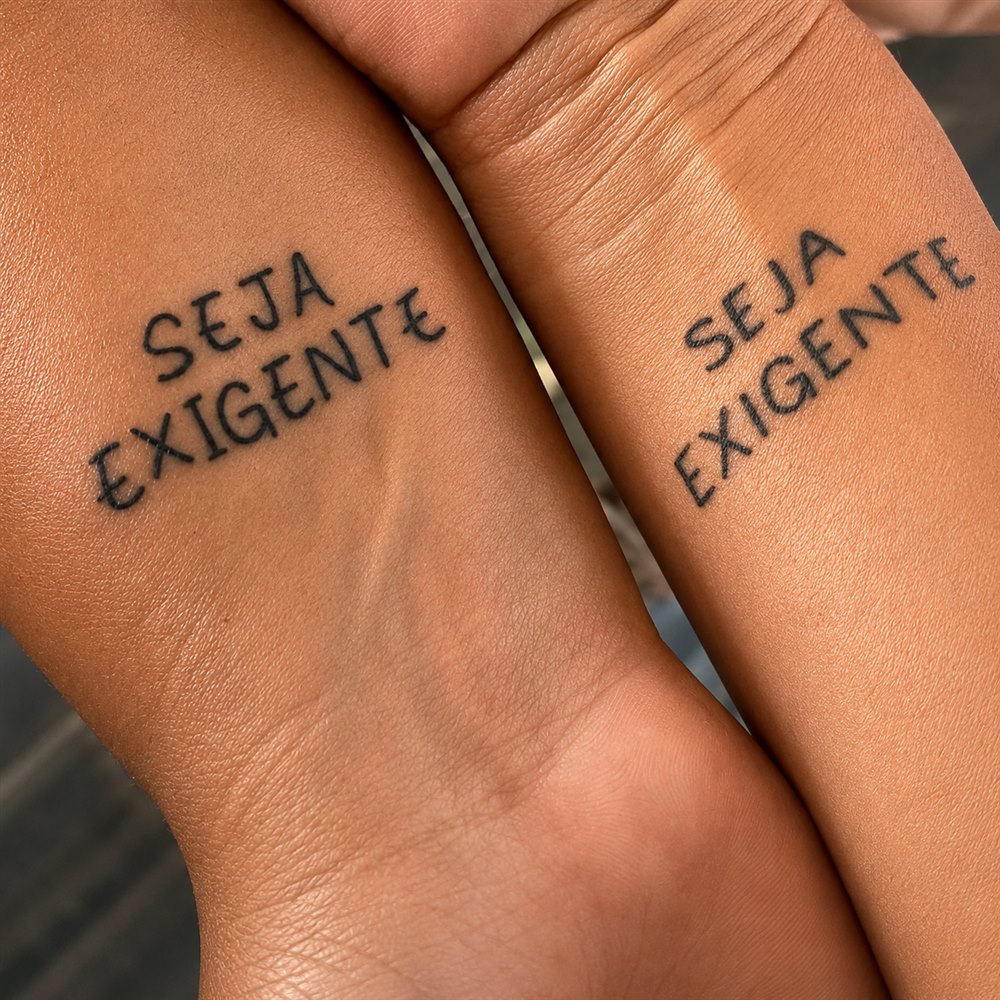 Dois pulsos lado a lado, cada um com 'Seja Exigente' tatuado