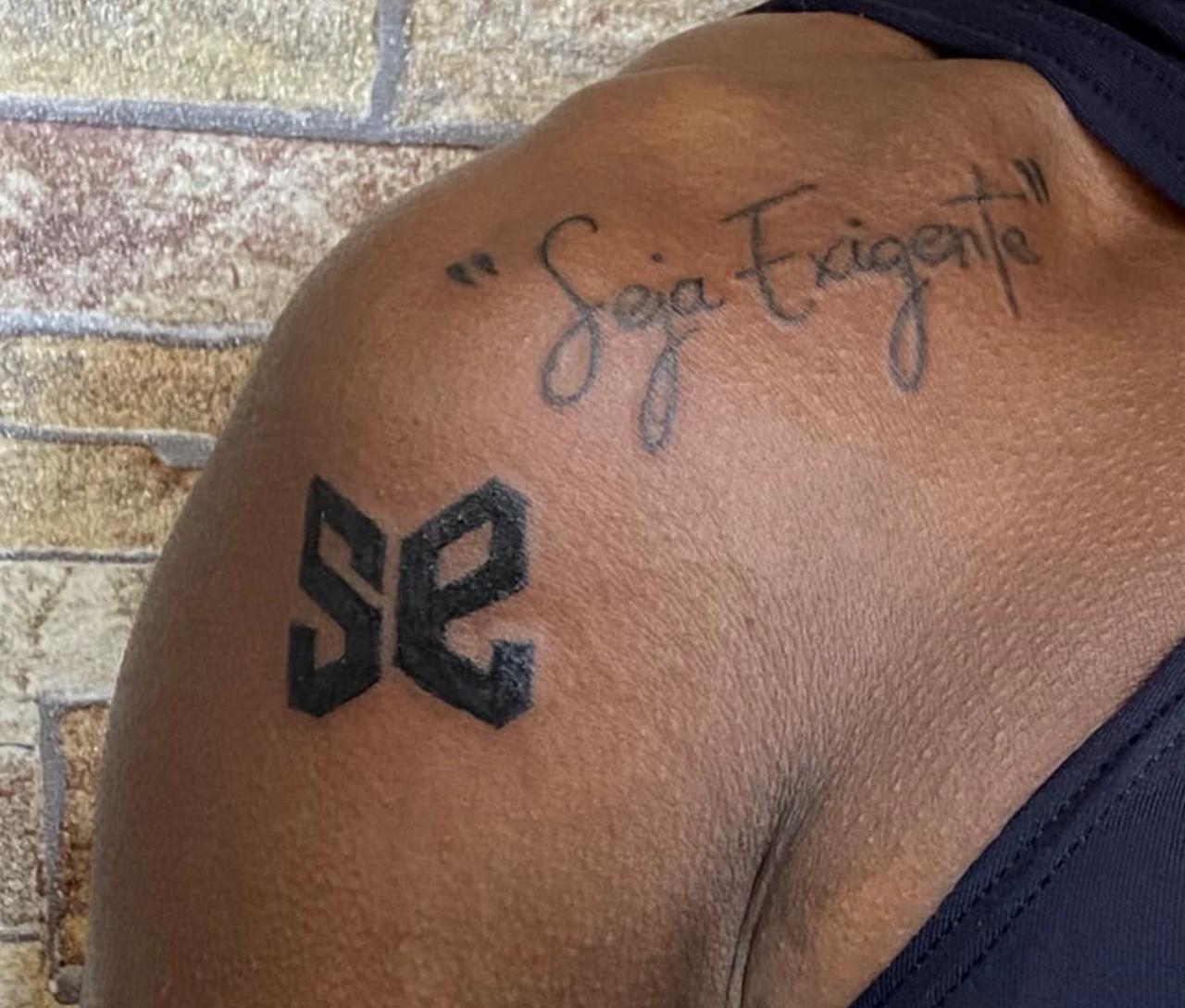 'Seja Exigente' e o símbolo SE tatuados no ombro